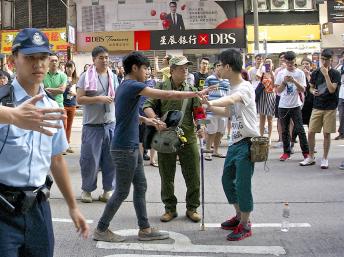 铜锣湾占领区警方已经加派警力防止黑帮捣乱，但仍有一些反佔中人士，如图中身穿绿色军服手臂缠上“为人民服务”布条的男子，与学生口角。（郑汉良摄）